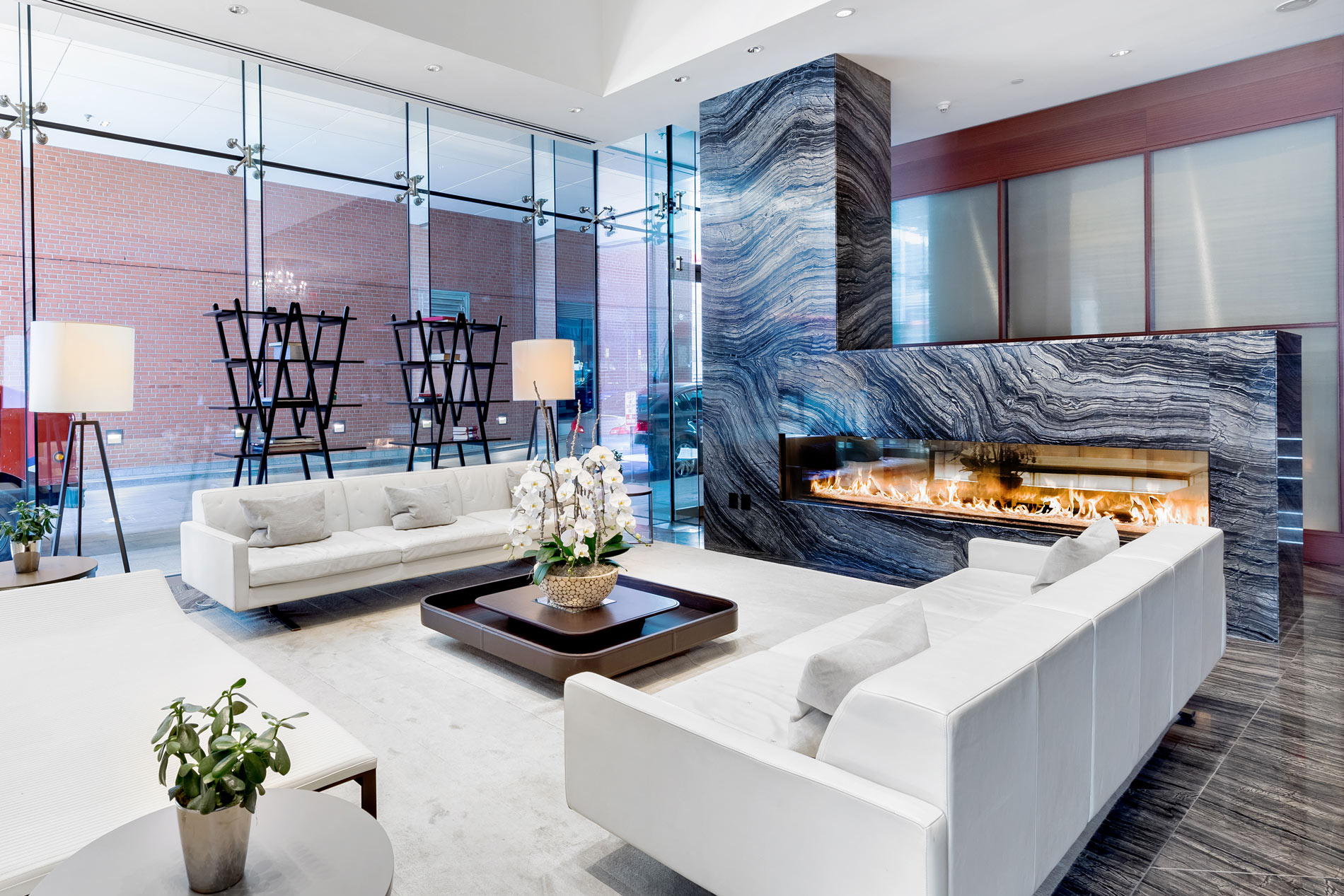 Modern luxury living space with white sofas and dramatic marble fireplace wall