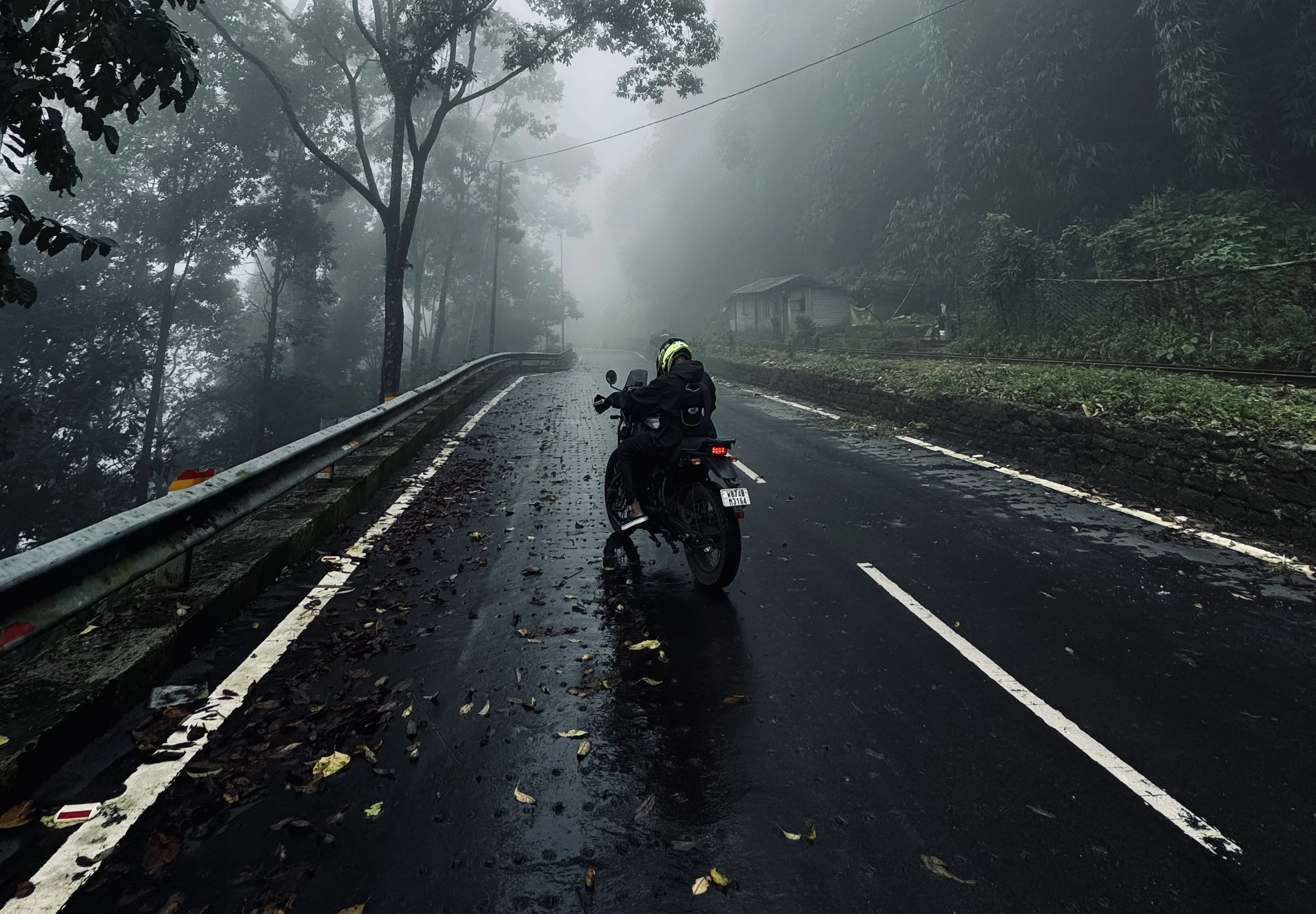 Motorcycle rider on a misty mountain road in the Himalayas. Affordable motorcycle rentals in Bagdogra for exploring North Bengal and Sikkim.