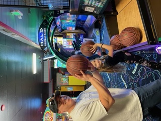 Ian King playing an arcade basketball game with a child at a family entertainment center.