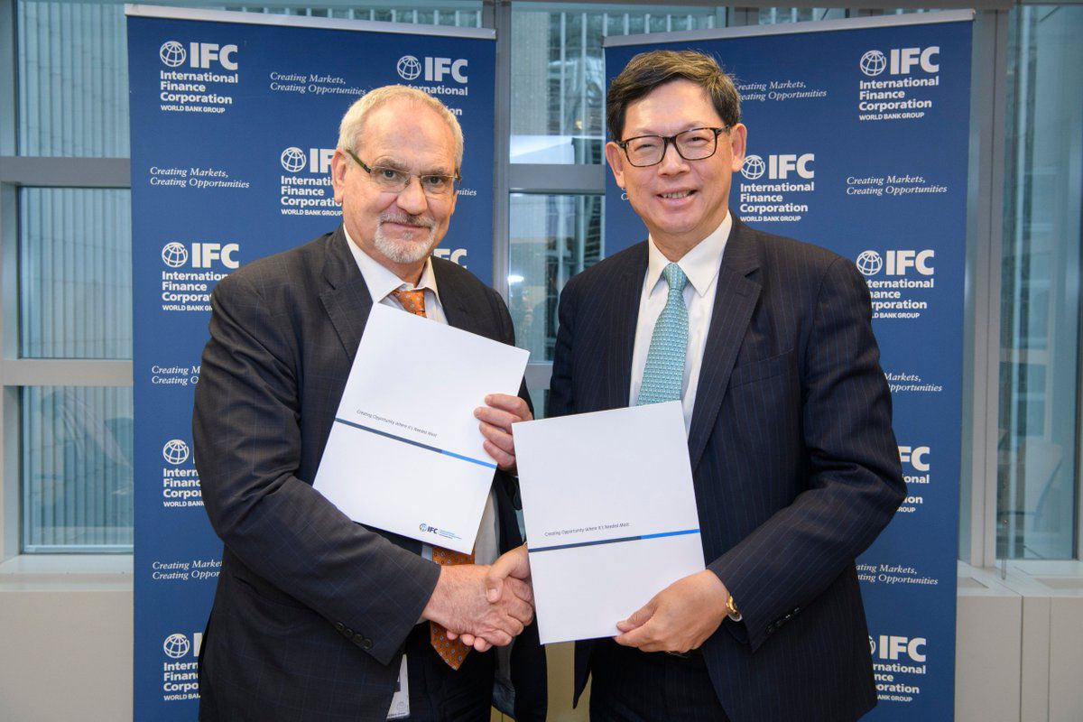 IFC representatives holding signed agreement documents at IFC headquarters