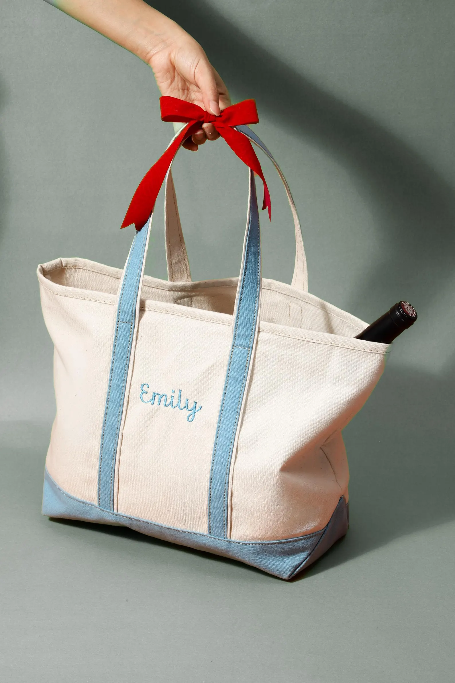 Personalized natural canvas tote with blue trim and a red ribbon