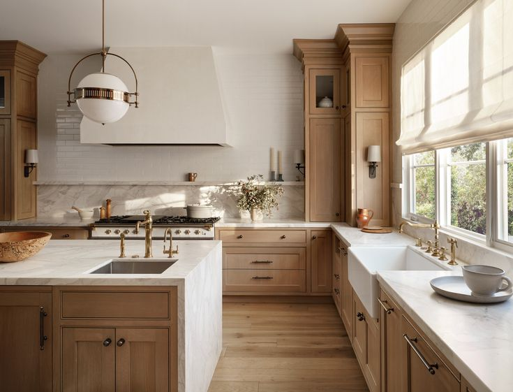 Warm wood kitchen with white marble countertops and brass fixtures
