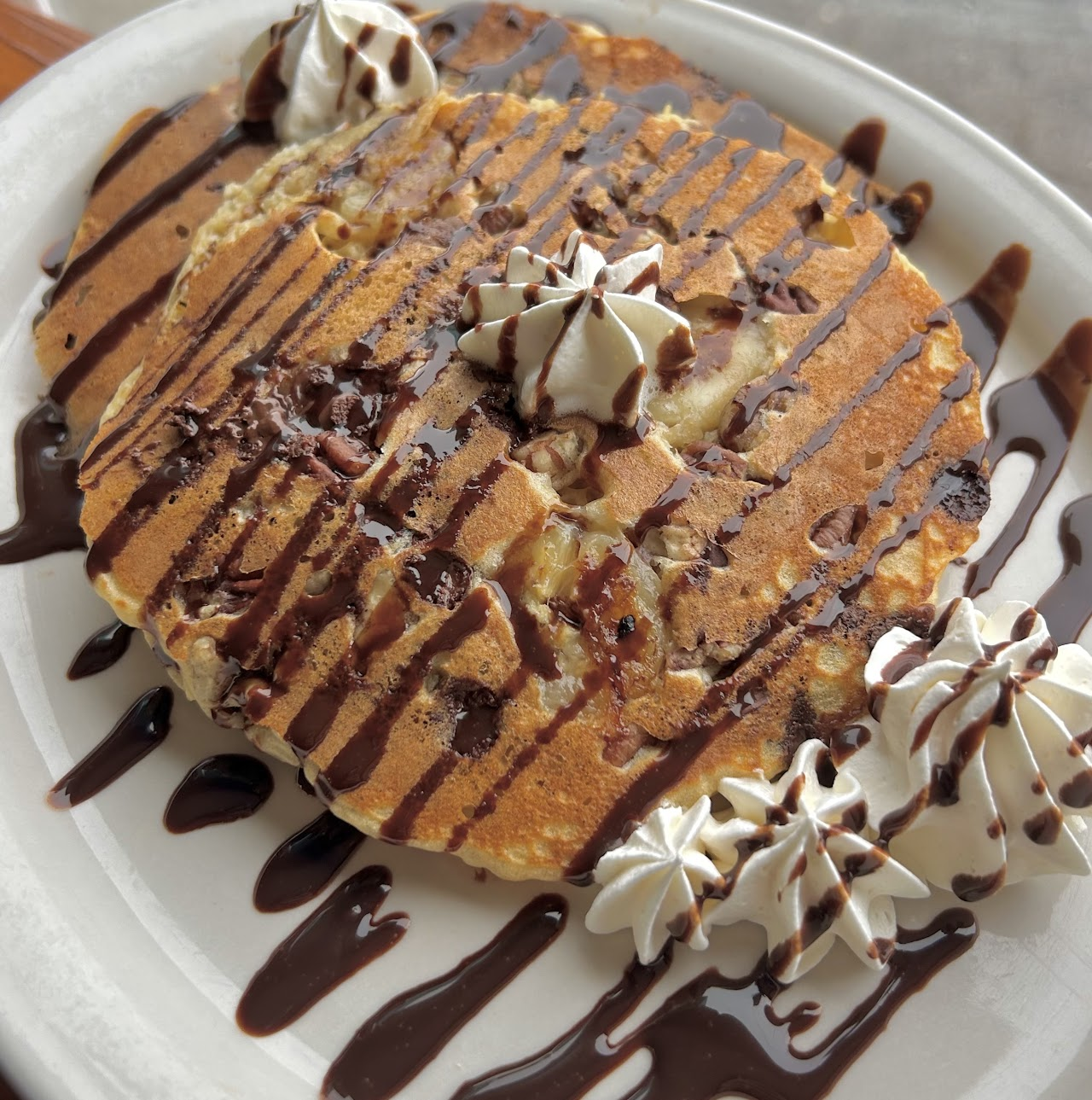 Chocolate chip pancakes with whipped cream and chocolate drizzle