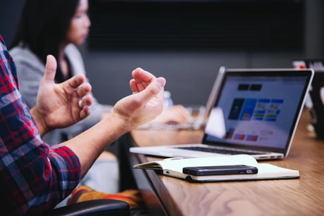 Business discussion with hands gesturing and laptop showing analytics