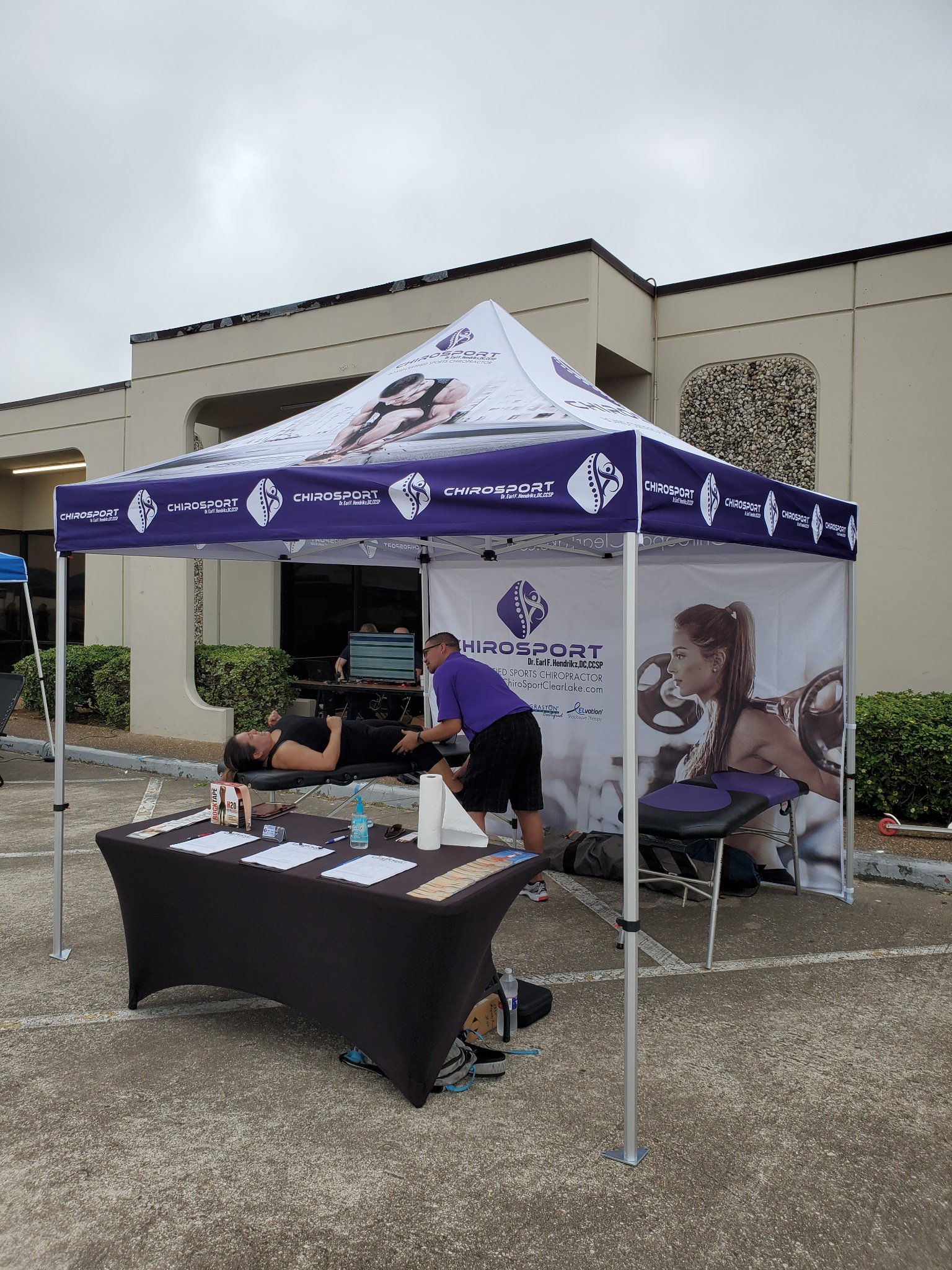 Full view of the sports chiropractic event booth with a patient being treated on the table