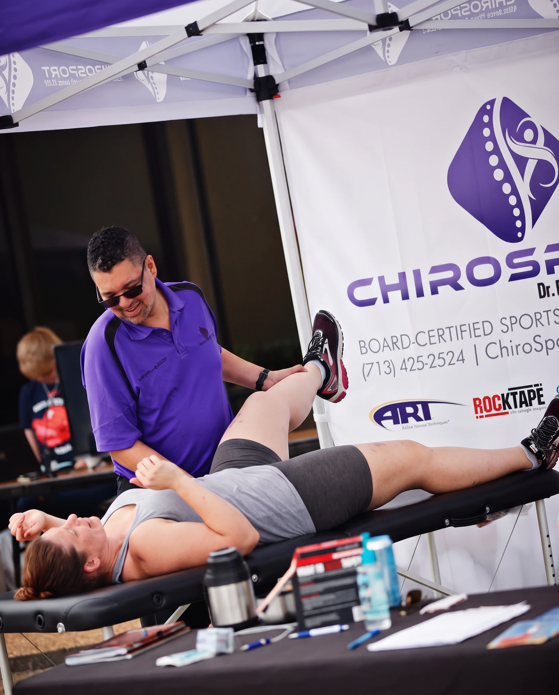 Dr. Hendrikz smiling while performing a straight-leg raise assessment on a patient at a race event
