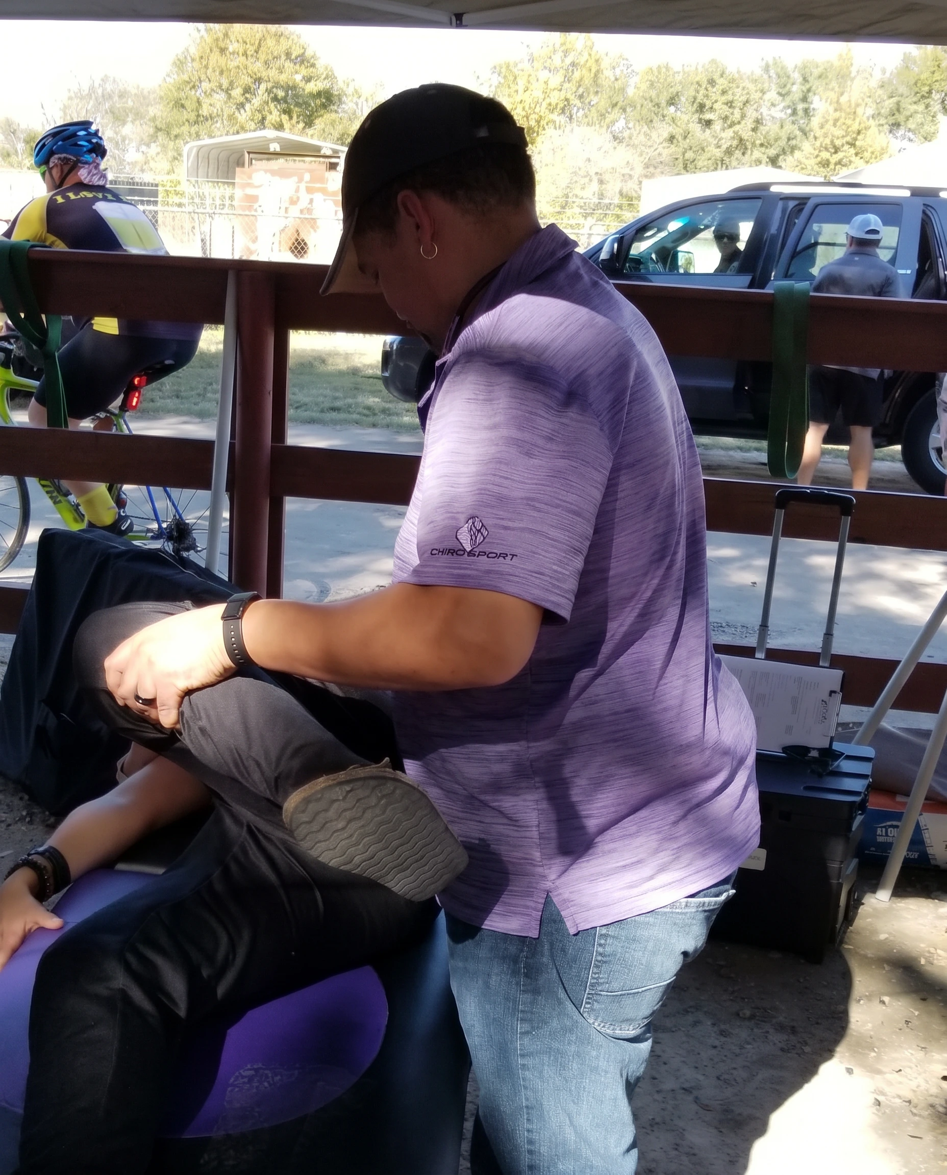 Dr. Hendrikz treating a cyclist at an outdoor cycling event along a trail