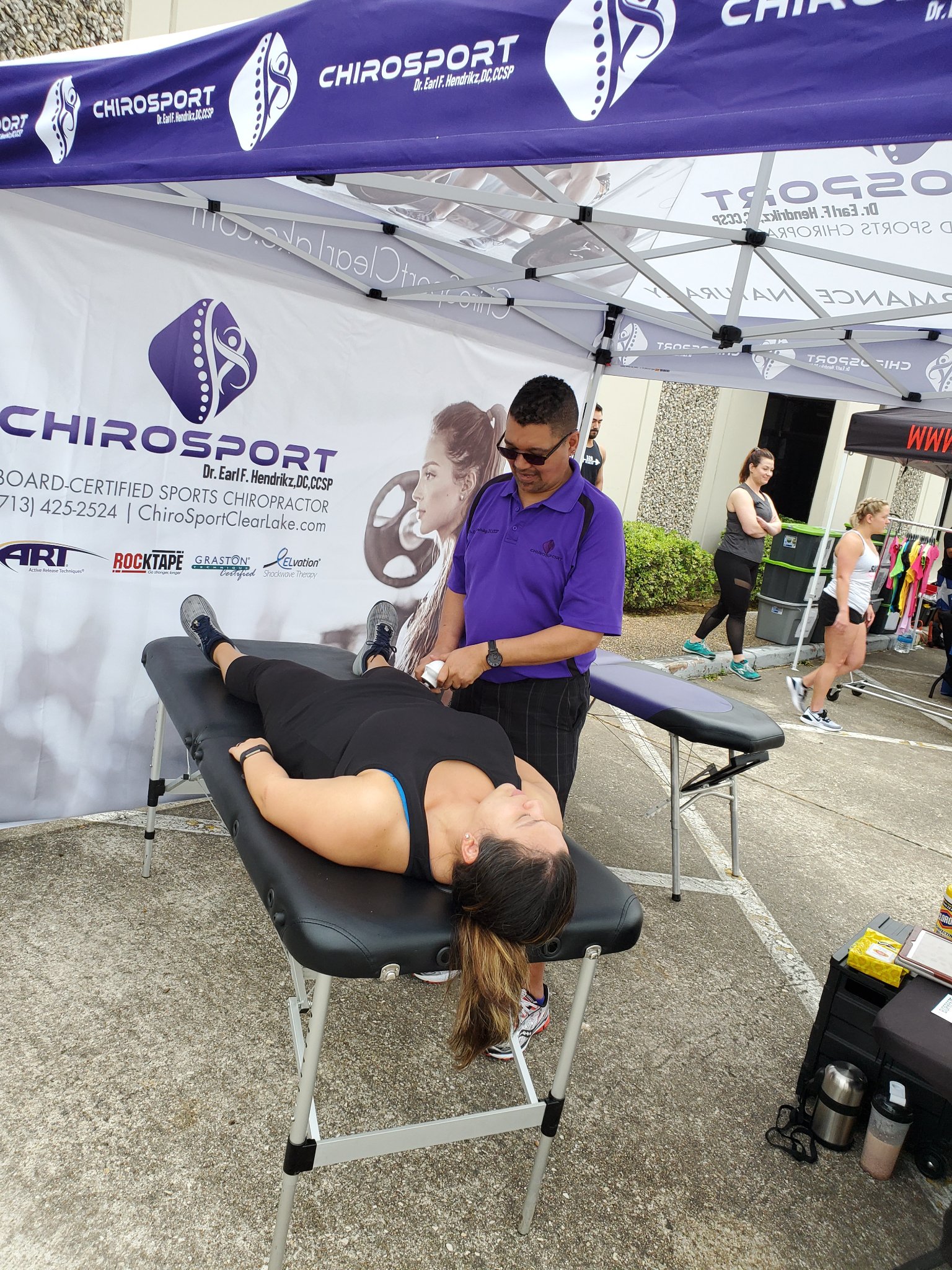 Dr. Hendrikz using an instrument-assisted tool on a patient's leg at an event booth