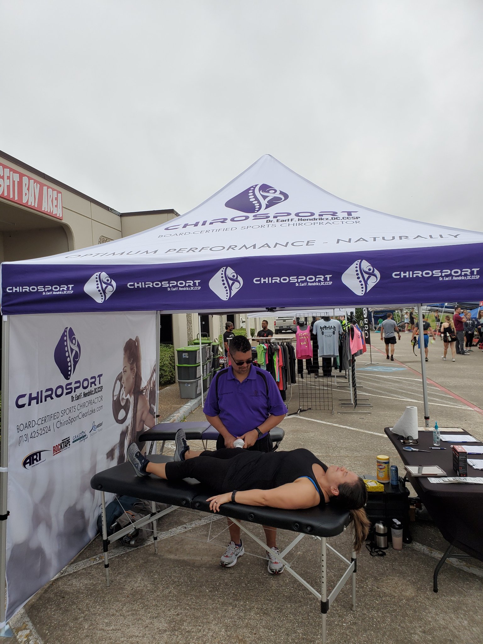 Dr. Hendrikz using a percussion tool on a patient at the event booth in front of CrossFit Bay Area
