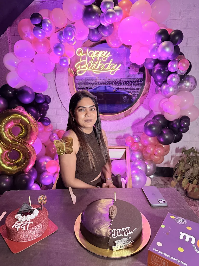 Birthday celebration with pink and purple balloon decorations and Happy Birthday neon sign