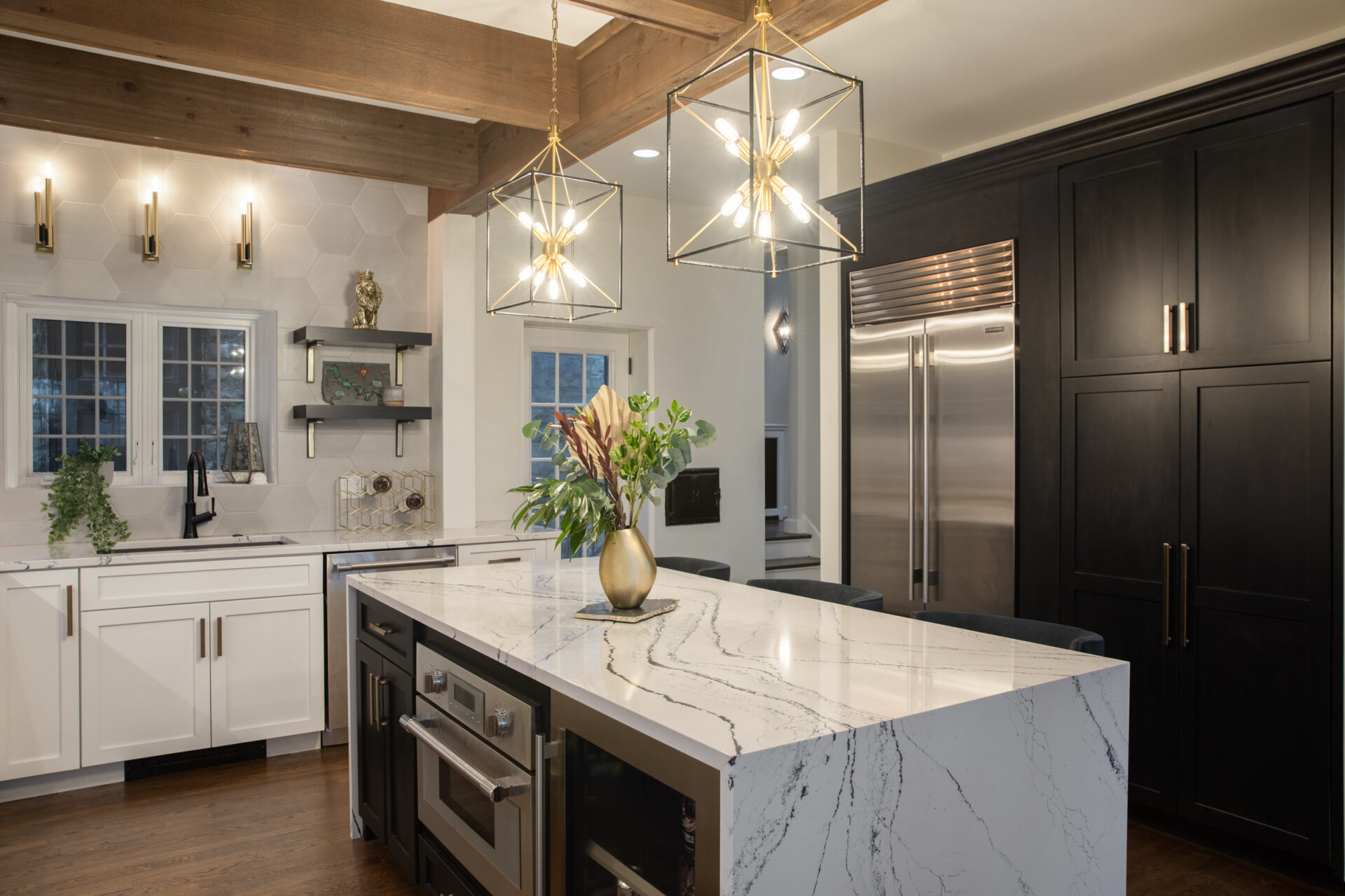 Dramatic dark kitchen with marble waterfall island and gold pendant lights by Modern Style Construction