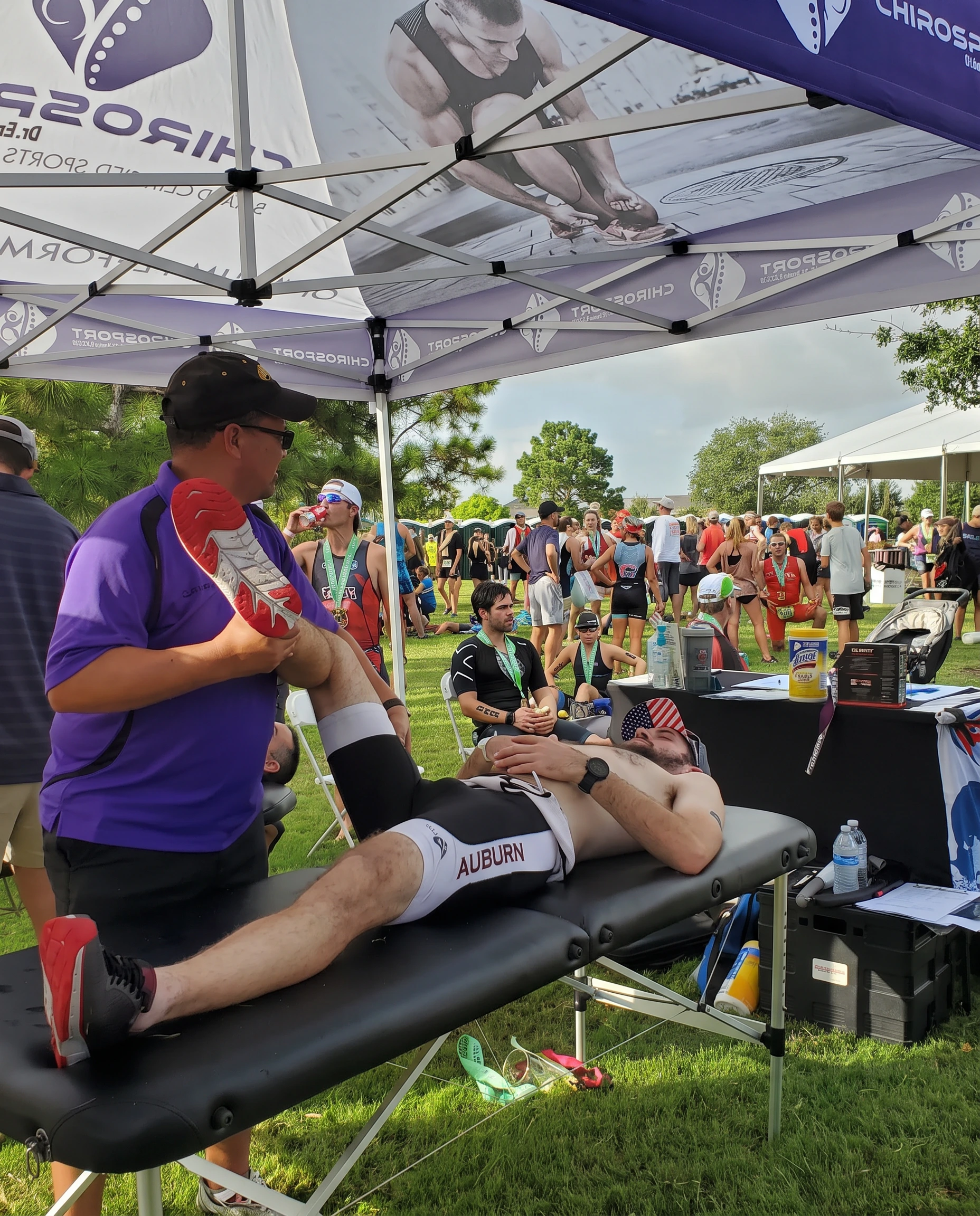 Dr. Hendrikz stretching a triathlete's leg at a busy race finish area