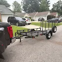 Small utility trailer hitched to a truck on a residential street