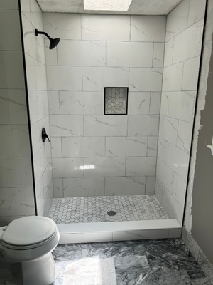 Walk-in shower with white marble tile and hexagonal mosaic floor