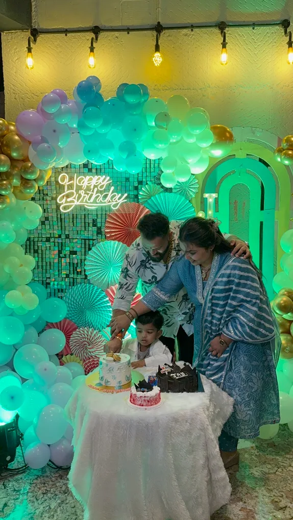 Family birthday party with colorful balloon arch and neon Happy Birthday sign