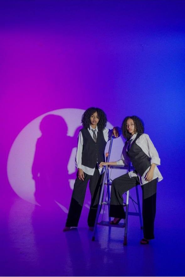 Two models in tailored looks under blue and purple lights