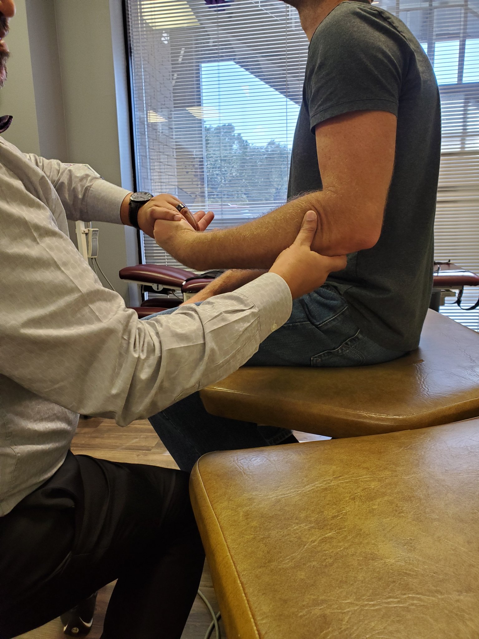 Close-up of an in-clinic muscle and arm assessment on a seated patient