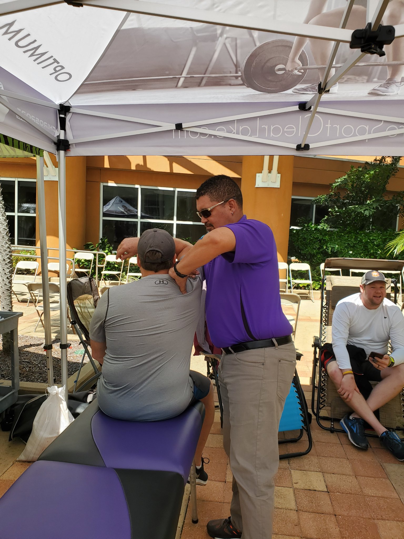Dr. Hendrikz adjusting a seated athlete's shoulder at an outdoor event