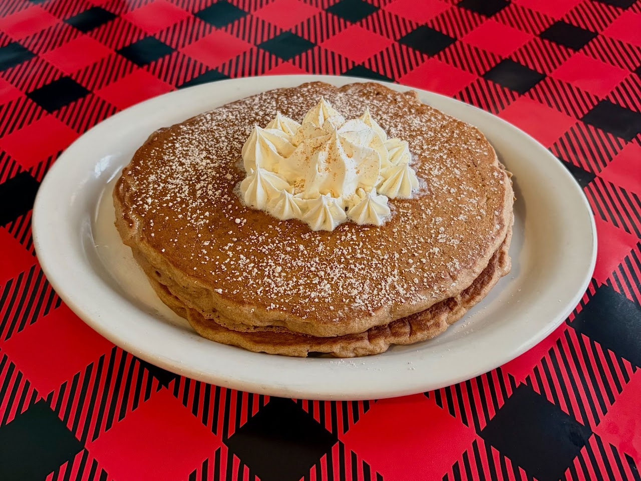 A stack of pancakes topped with whipped cream