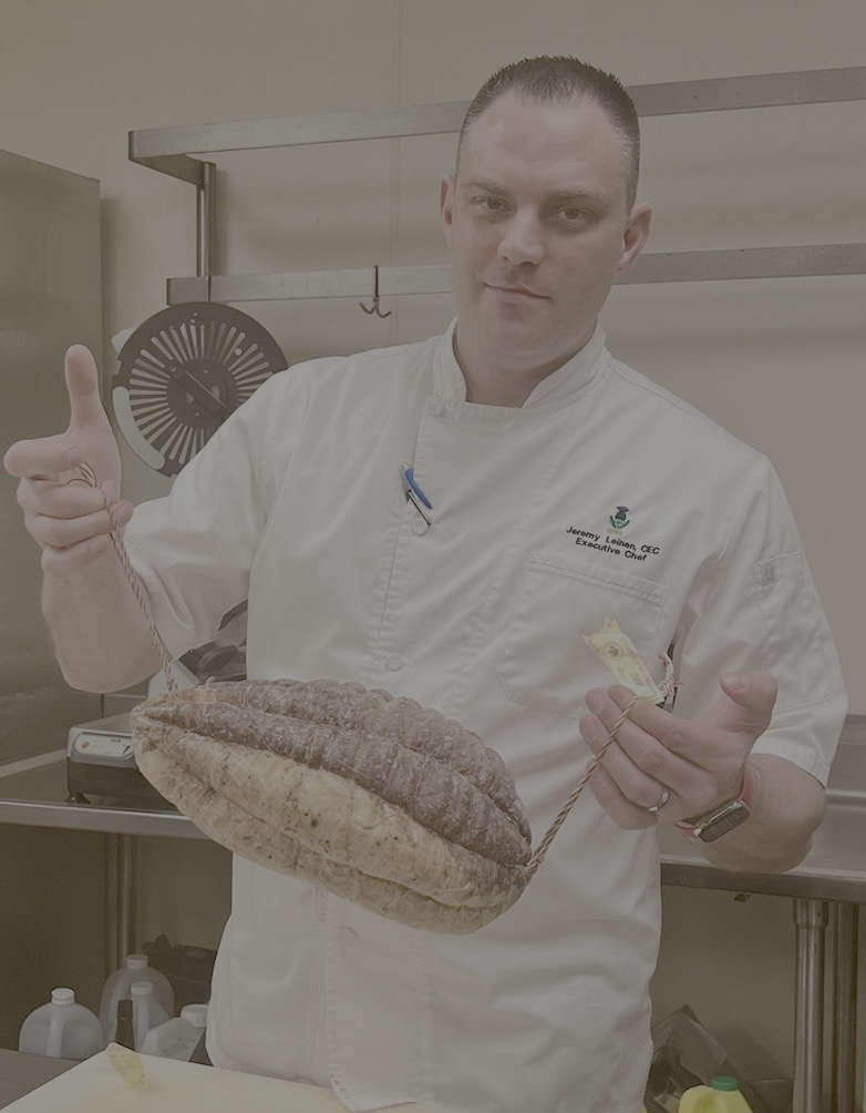 Jeremy Leinen holding a large rustic loaf, finger raised