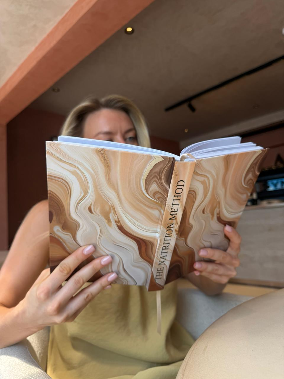 Woman reading the caramel marble edition of The Natrition Method journal