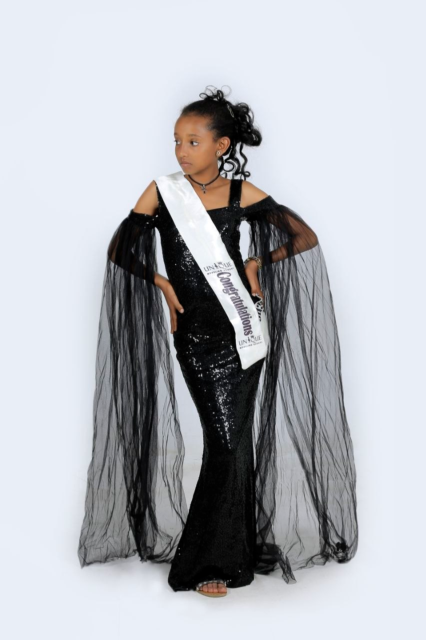 Child model in a black sequined gown with a sash