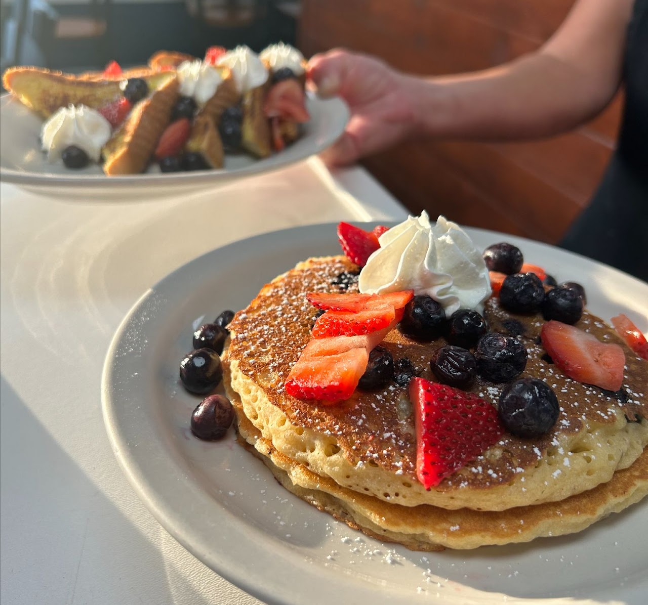 A plate of biscuits and gravy with pancakes in the background