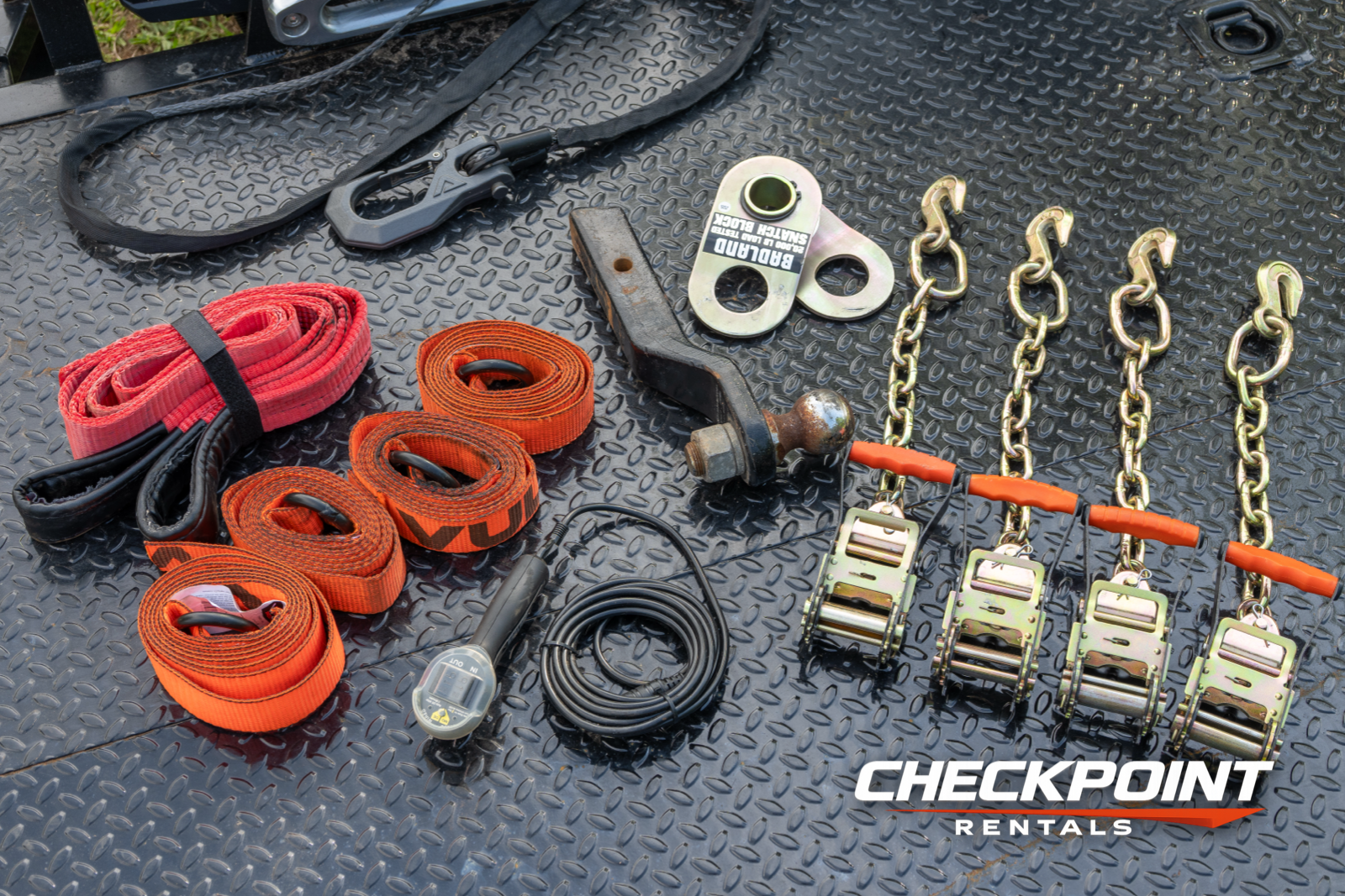 Included accessories: straps, chains, ratchets, winch hook laid out on diamond plate deck