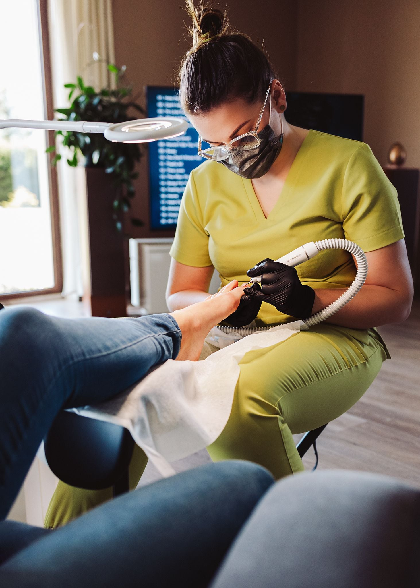Karolina Szynwelska wykonująca zabieg podologiczny na stopie pacjenta w domowym otoczeniu