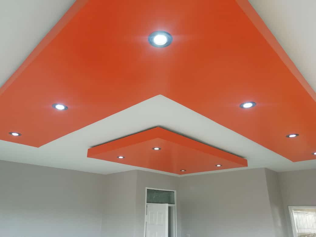Bold orange accent ceiling design with spotlights