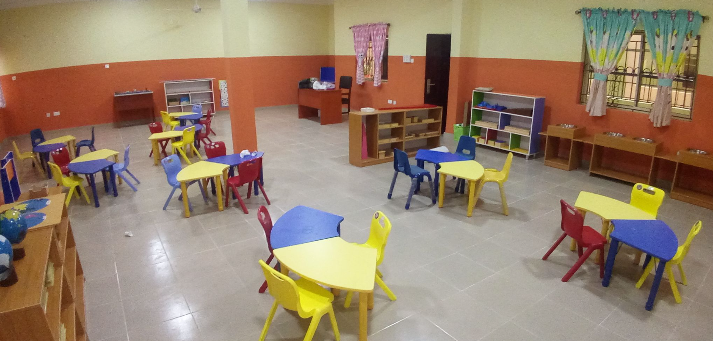 Bright early-years classroom with kid-sized tables and Montessori shelves