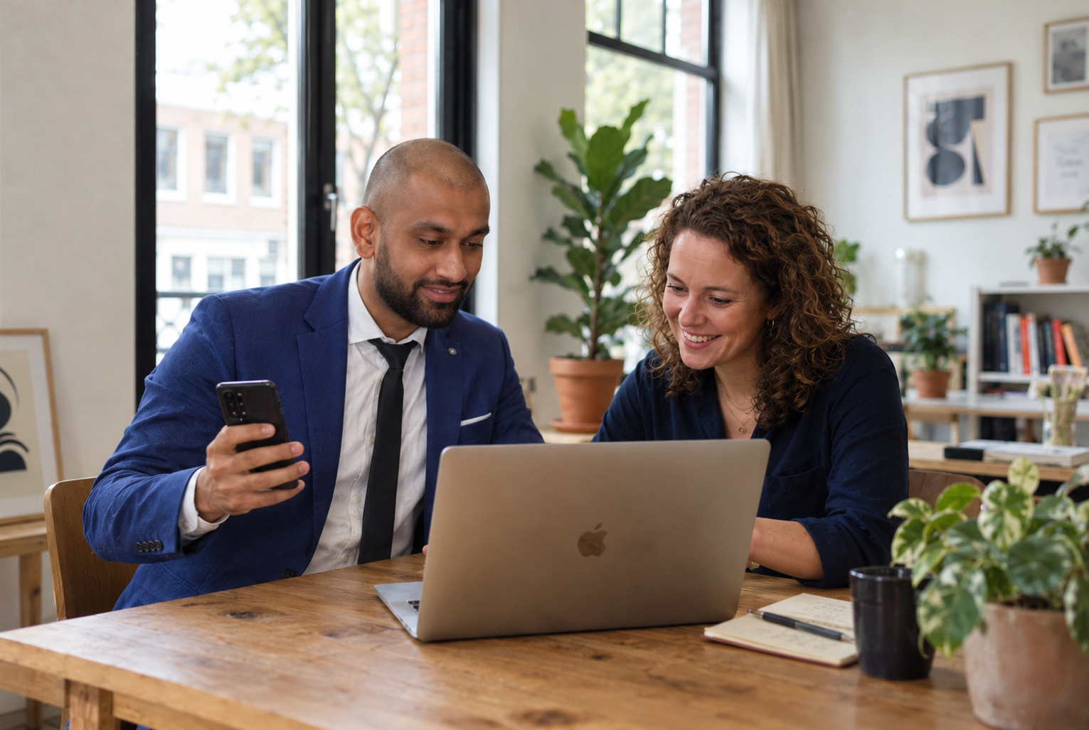 Twee ondernemers bespreken samen een website aan tafel met een laptop
