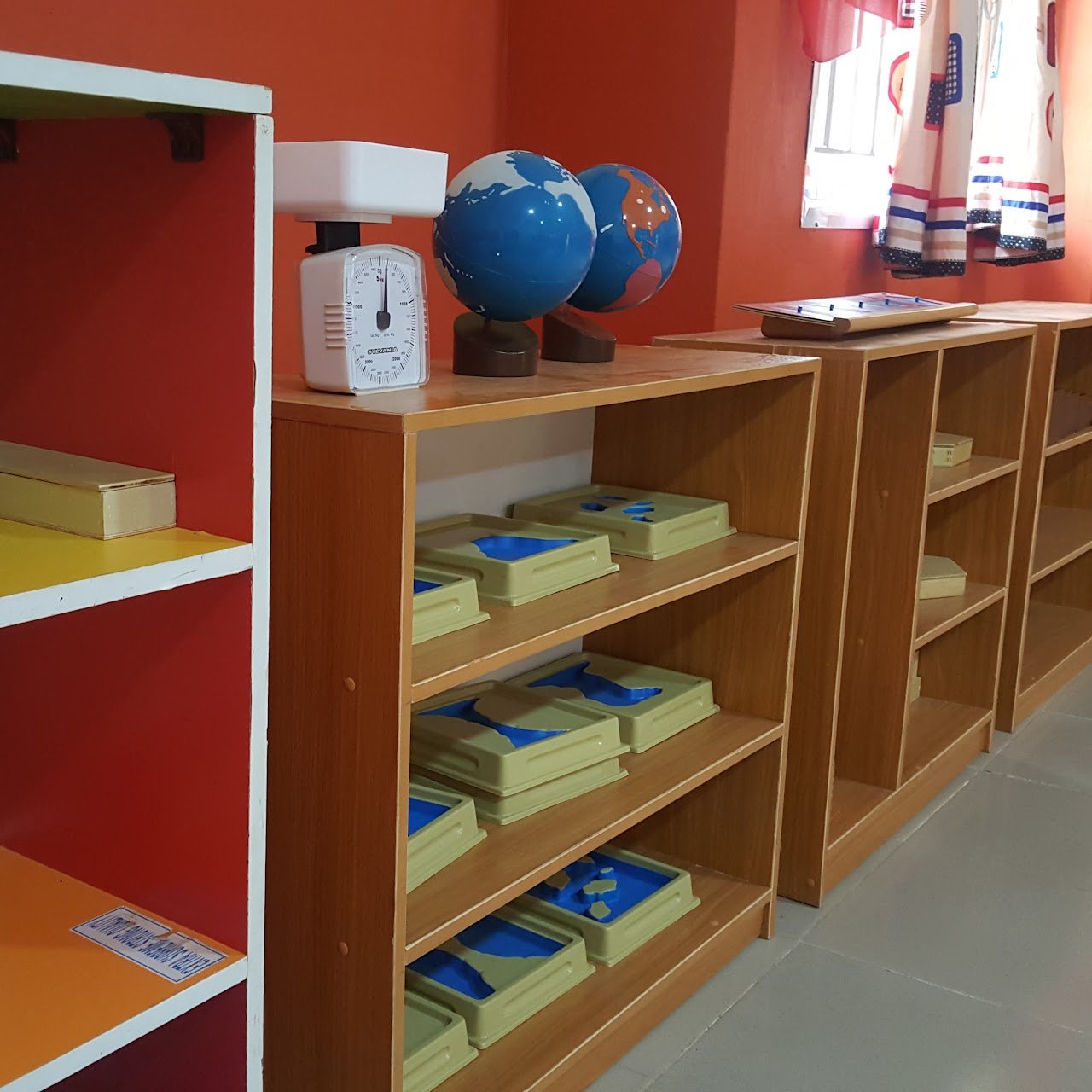 Montessori material shelves with globes and a weighing scale