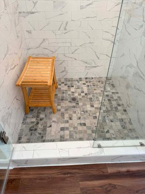 Shower interior with white marble-look tiles and bamboo bench