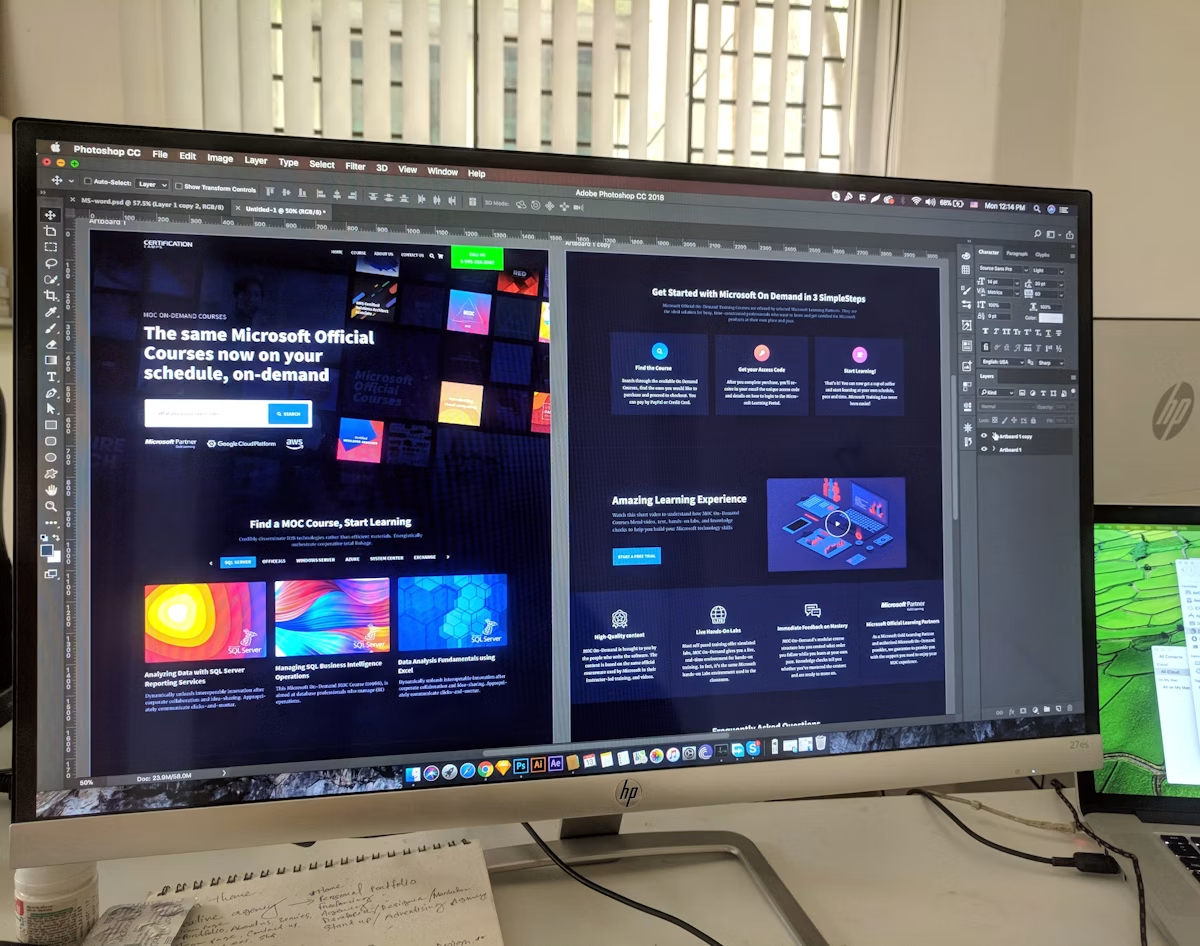 Website designs being refined in Photoshop on a large monitor