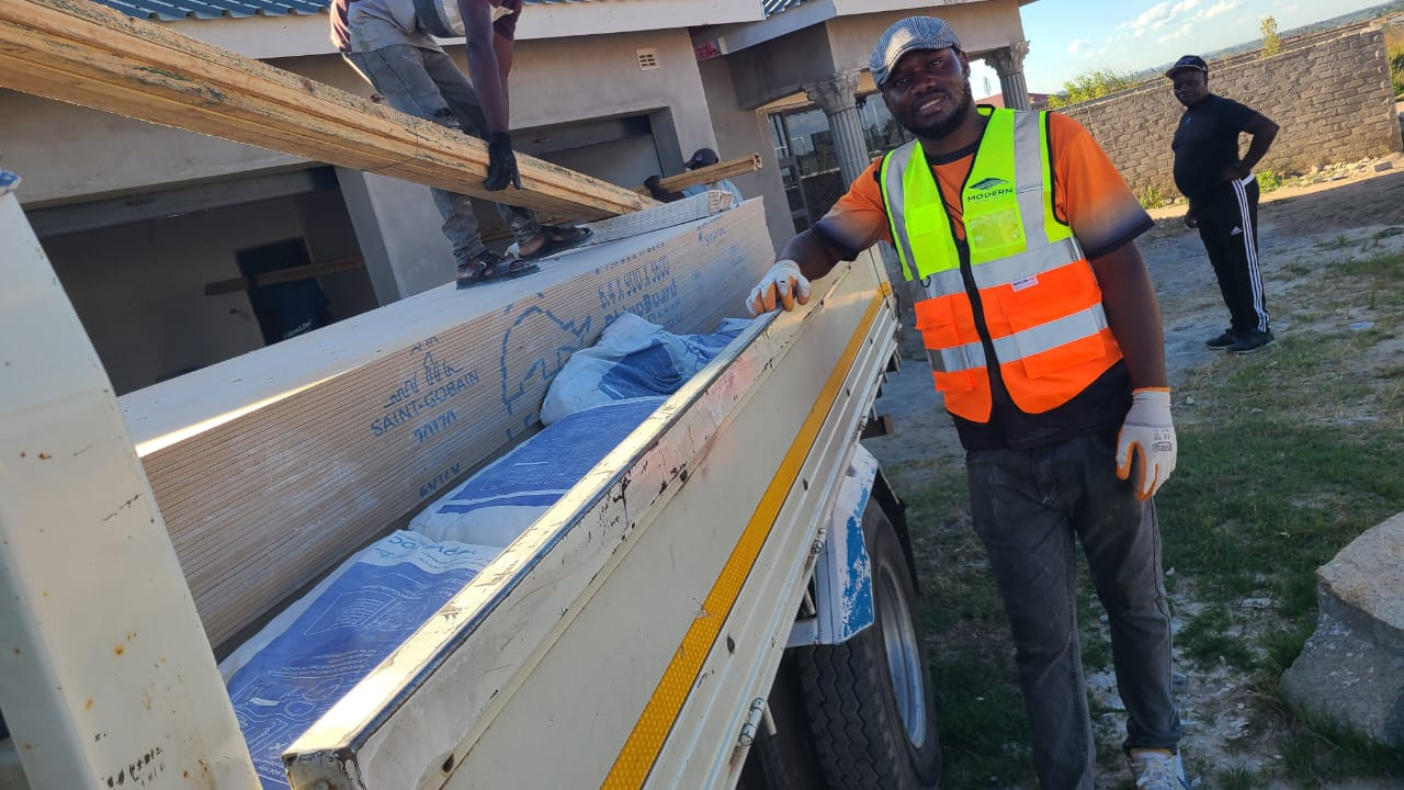 Worker in orange hi-vis vest unloading Saint-Gobain plasterboard from a truck