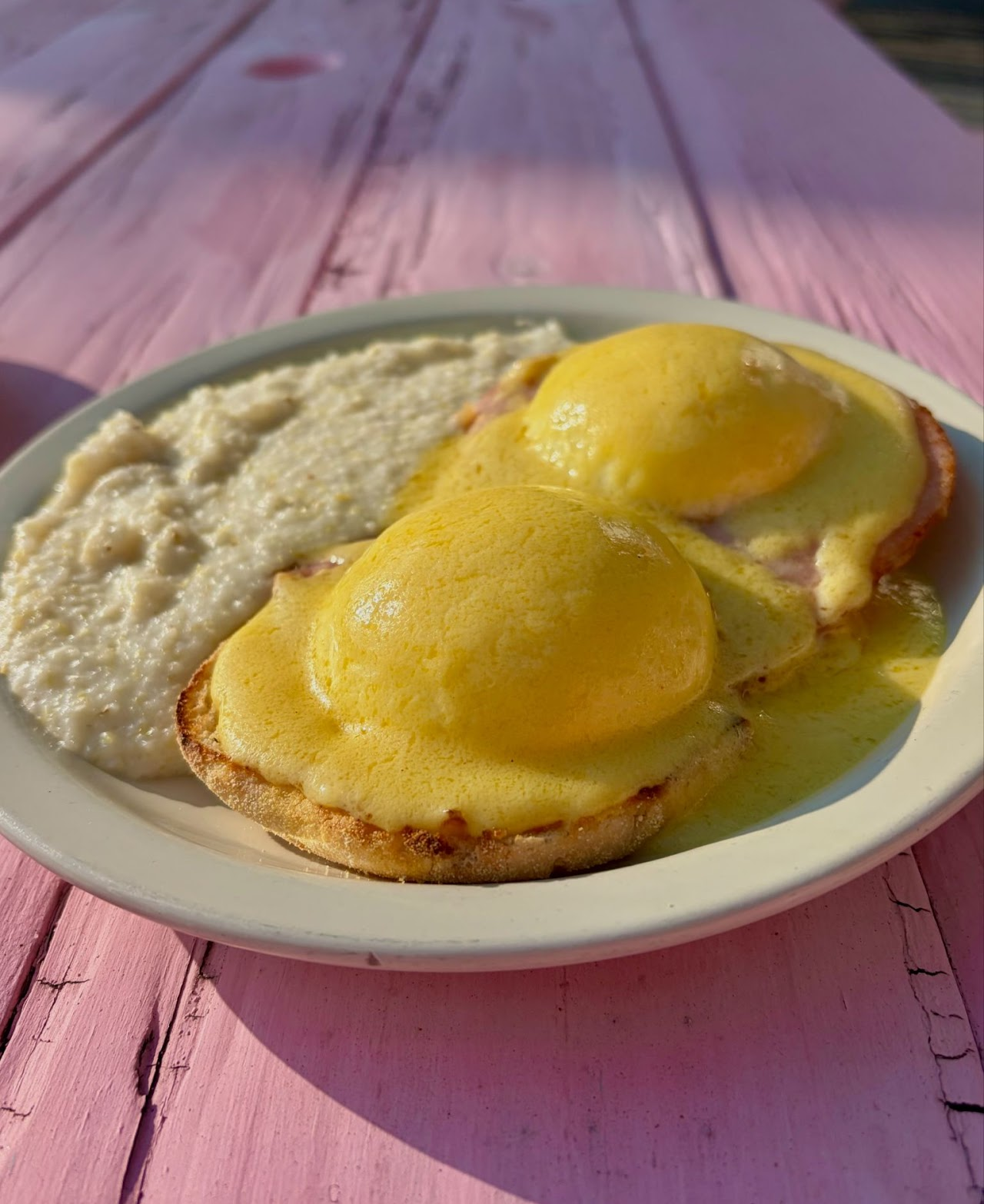 Eggs Benedict with grits on a pink outdoor table