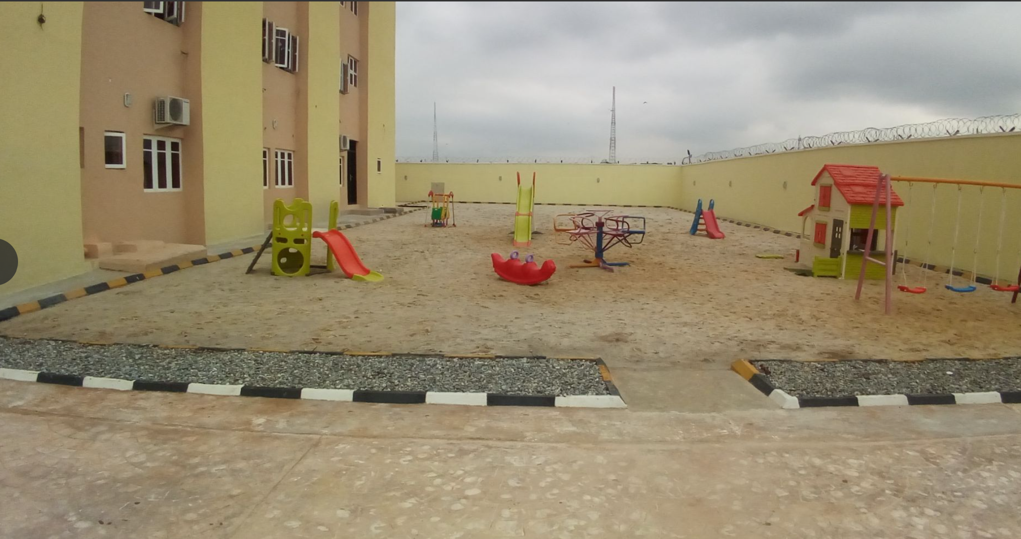 Wide view of the school play area with swings and a playhouse