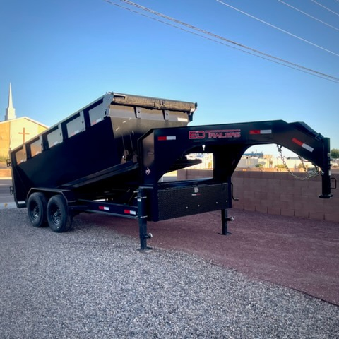 Black gooseneck roll-off dumpster trailer parked by a brick wall in Albuquerque, NM
