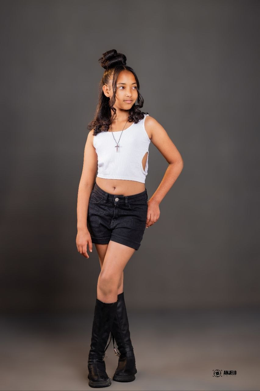 Model in a white crop top and black shorts