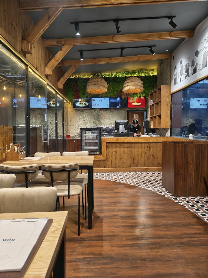 WaB Cafe warm wooden interior with greenery, pendant lights, and comfortable seating