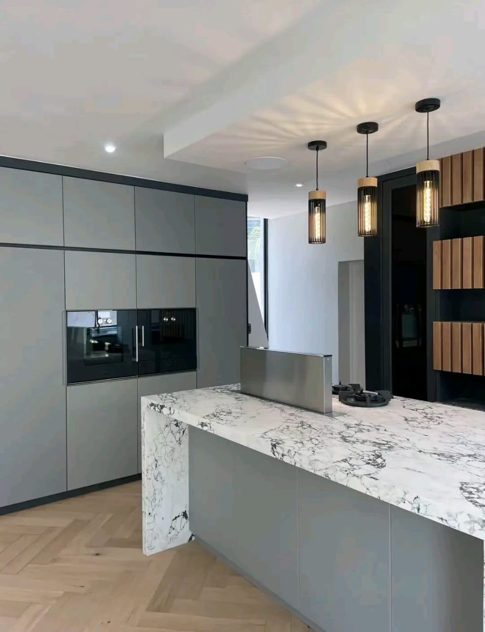 Luxury kitchen with white marble waterfall island and cage pendant lights