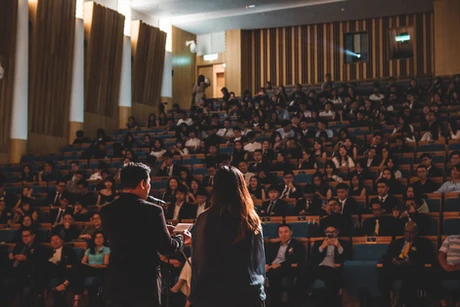 Presenters speaking to a large audience in an auditorium