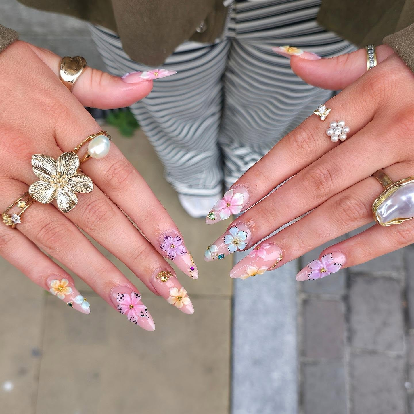 Pink nail art with various flower designs and gold accents