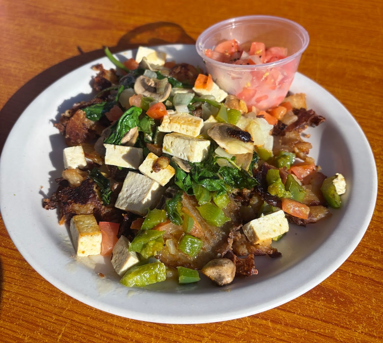A savory breakfast plate with greens, mushrooms, peppers, and tofu