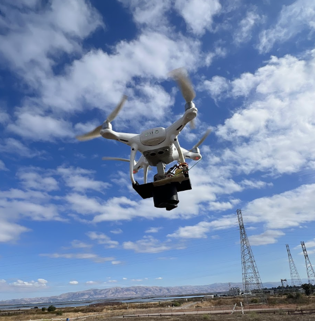 Drone carrying a seed dispersal mechanism over a test landscape