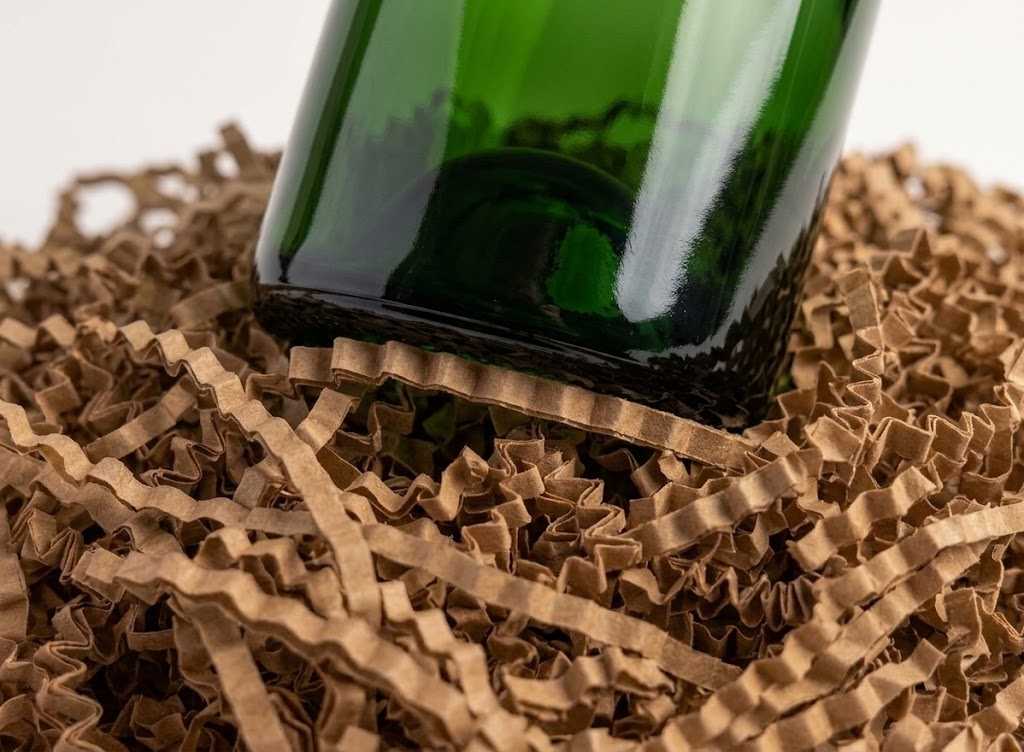 Base d’une bouteille verte posée sur une frisure kraft en zig-zag