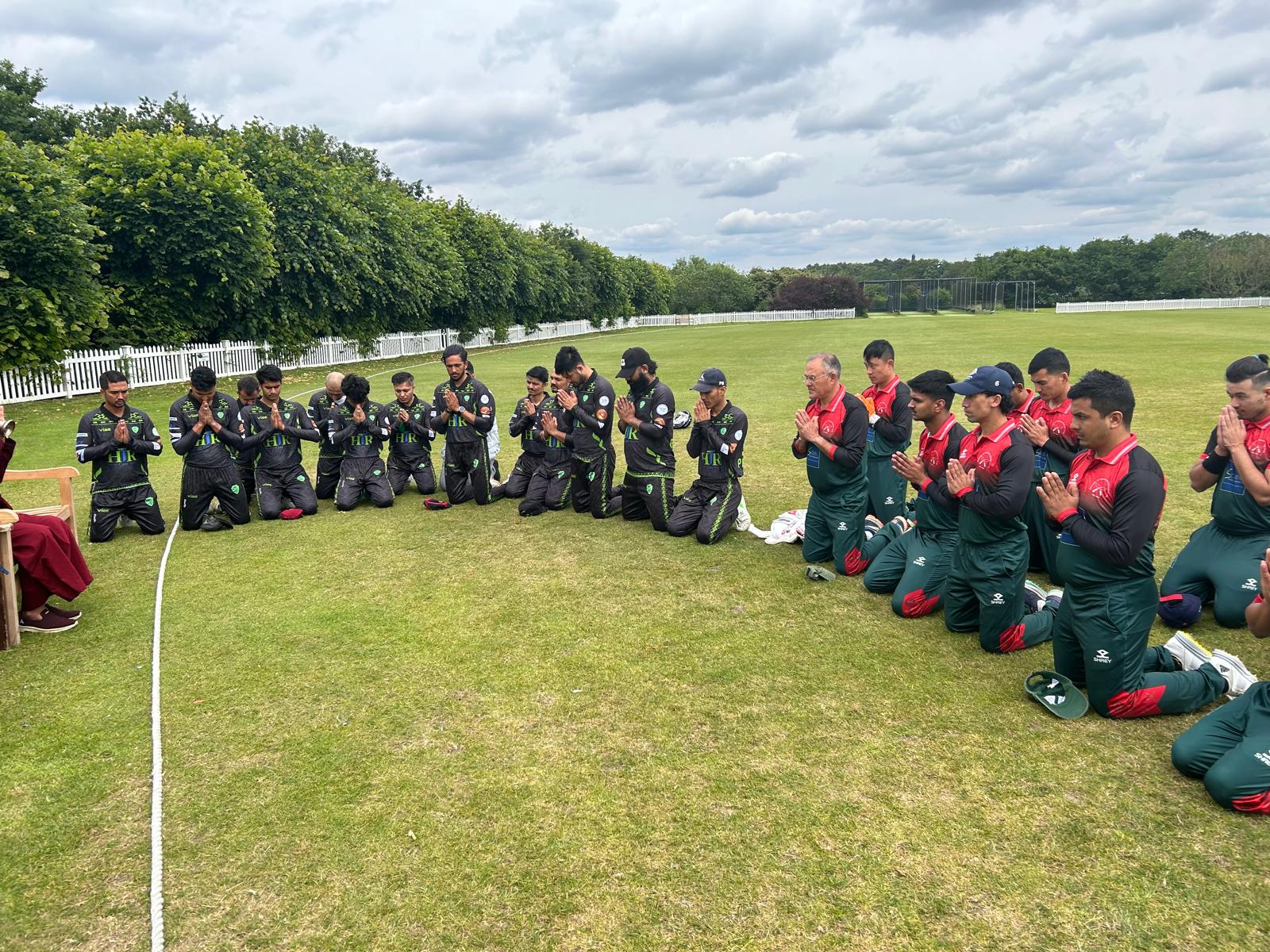 Cricket teams in prayer on the field