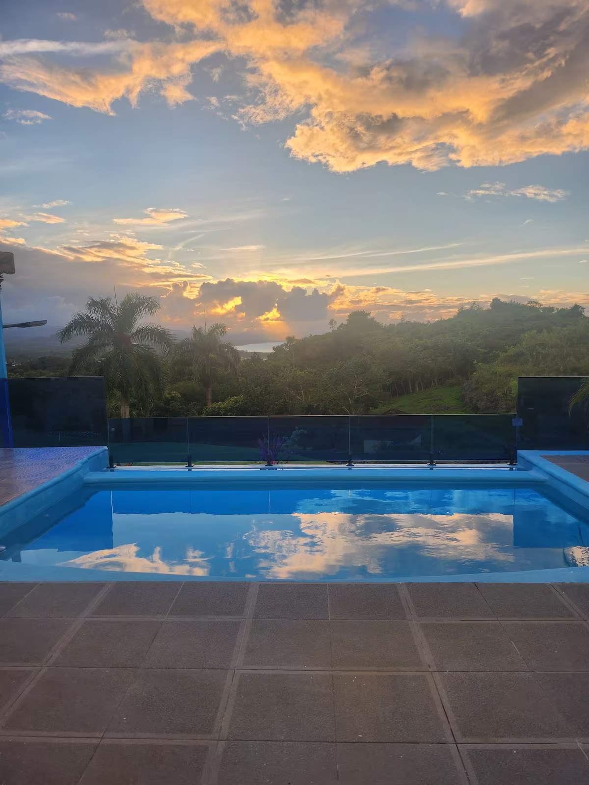 Piscina infinity al atardecer con nubes doradas reflejadas en el agua