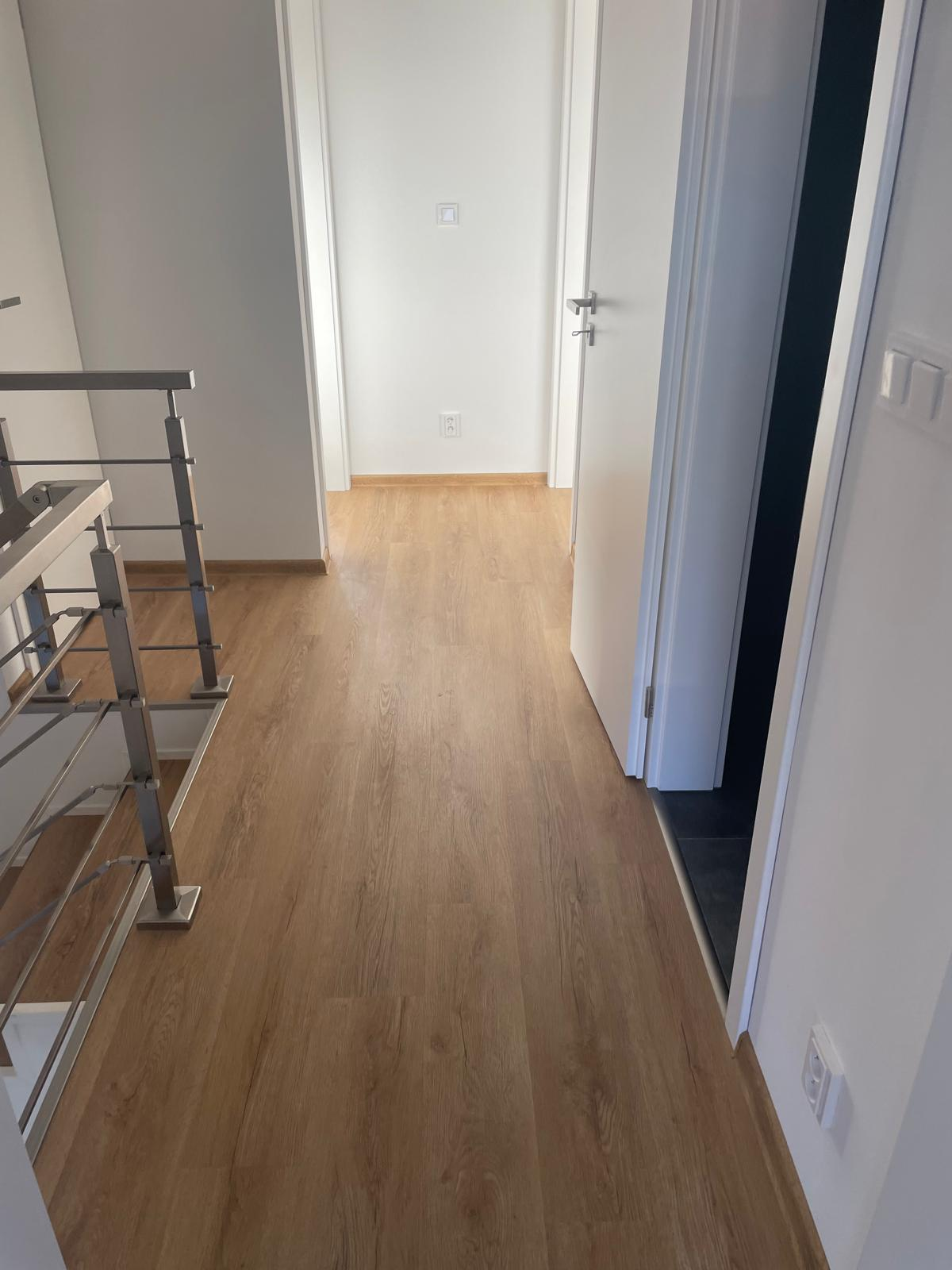 Realizace podlahy — větší otevřený prostor s šedou vinylou